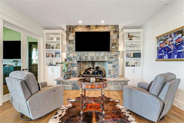 living room featuring a stone fireplace, light hardwood / wood-style flooring, and built in features