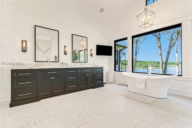 bathroom with a towering ceiling, vanity, a bathtub, and a notable chandelier