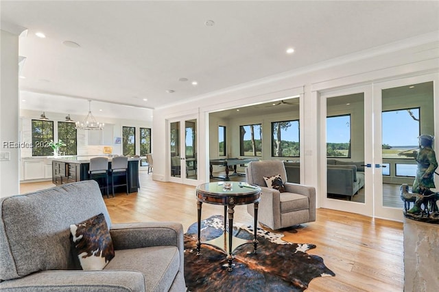 living room with french doors, a notable chandelier, and light wood-type flooring