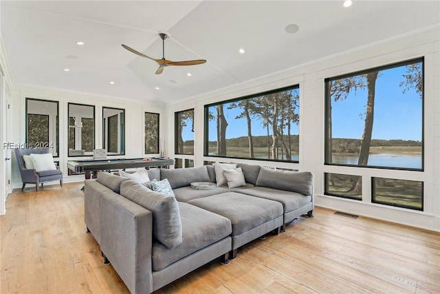 living room featuring ornamental molding, a water view, lofted ceiling, and light hardwood / wood-style floors