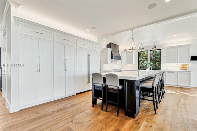 kitchen featuring a breakfast bar, tasteful backsplash, custom exhaust hood, hanging light fixtures, and a large island