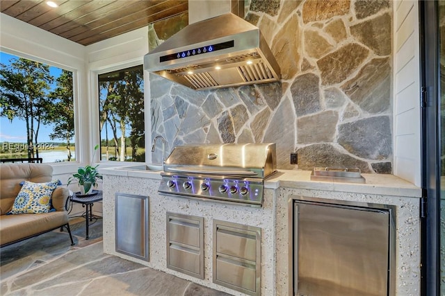 patio terrace at dusk featuring area for grilling, exterior kitchen, and sink