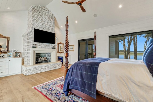 bedroom with lofted ceiling, access to outside, ceiling fan, light hardwood / wood-style floors, and a brick fireplace