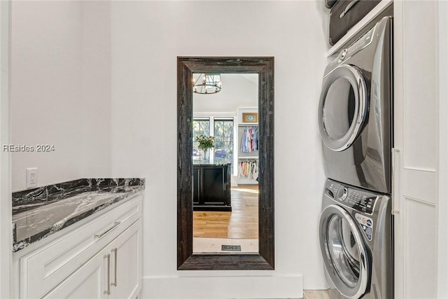 laundry area with stacked washer / drying machine and cabinets