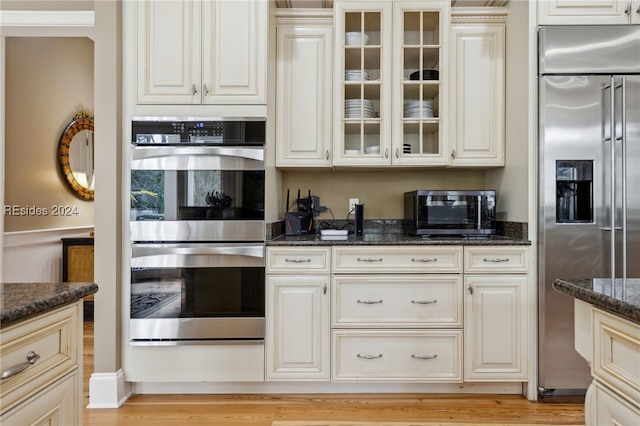 kitchen featuring light hardwood / wood-style flooring, stainless steel appliances, and dark stone counters