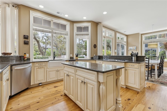 kitchen featuring stainless steel appliances, a center island, light wood-type flooring, and dark stone counters