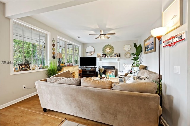 living room featuring wood-type flooring, a tile fireplace, and ceiling fan