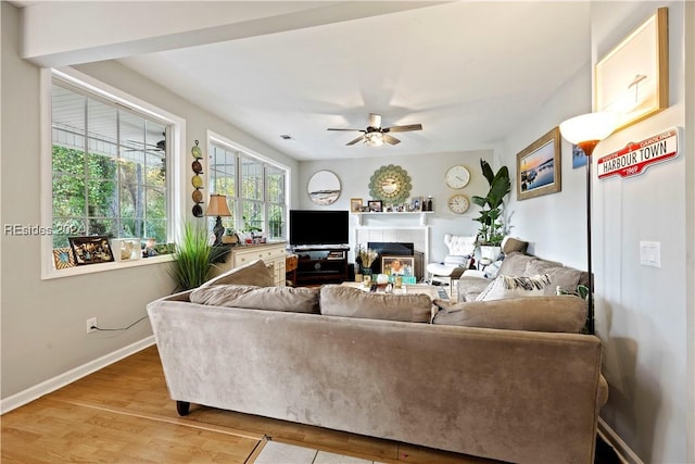 living room with hardwood / wood-style flooring, a tile fireplace, and ceiling fan