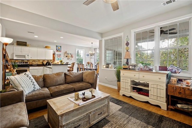 living room featuring hardwood / wood-style flooring and ceiling fan with notable chandelier