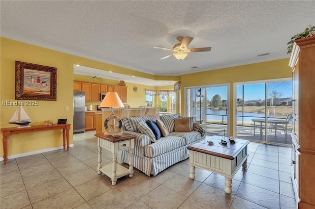 living room with light tile patterned floors, ceiling fan, a textured ceiling, and a water view