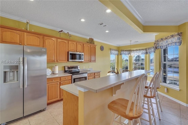 kitchen with light tile patterned flooring, crown molding, hanging light fixtures, a textured ceiling, and stainless steel appliances