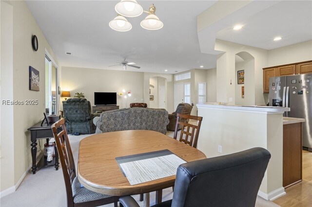 dining space featuring ceiling fan and light colored carpet