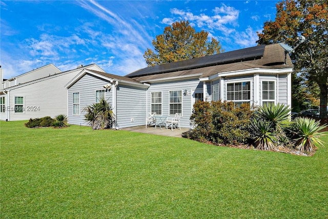 back of house featuring a lawn, a patio, and solar panels