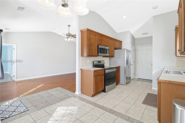 kitchen with sink, light tile patterned floors, ceiling fan, appliances with stainless steel finishes, and tasteful backsplash