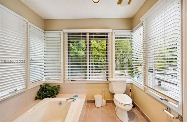 bathroom with tile patterned flooring, a washtub, and toilet