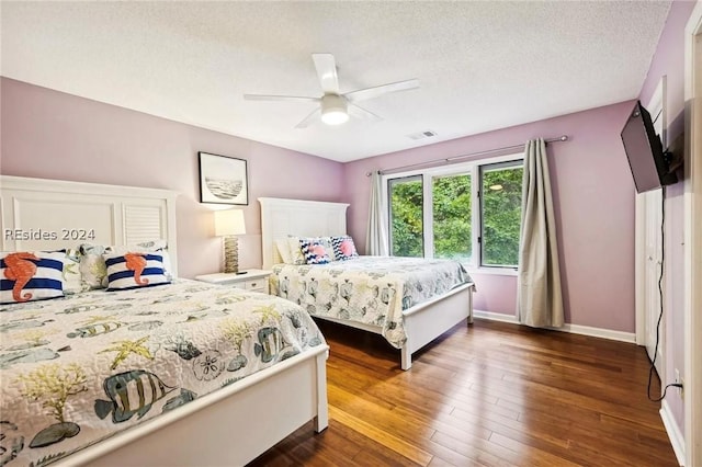 bedroom featuring ceiling fan, dark hardwood / wood-style flooring, and a textured ceiling