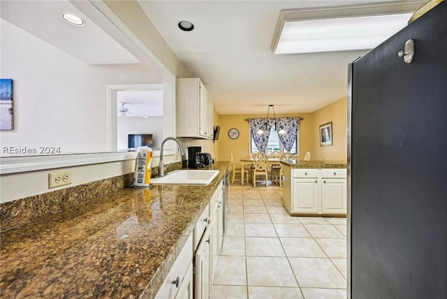 kitchen featuring sink, white cabinetry, decorative light fixtures, light tile patterned floors, and stainless steel fridge