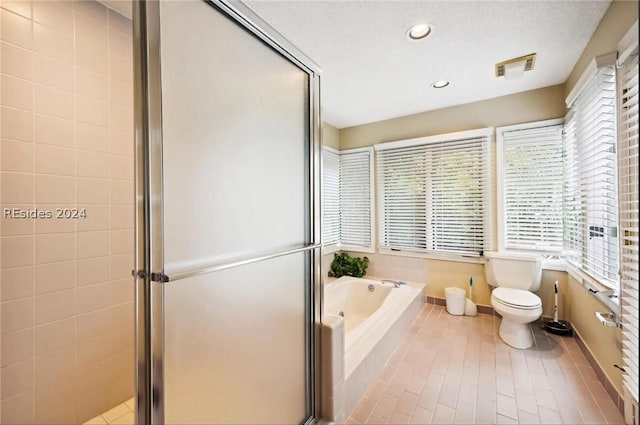 bathroom featuring tile patterned flooring, shower with separate bathtub, a textured ceiling, and toilet