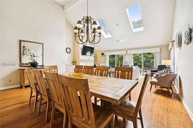 dining area featuring a skylight, beam ceiling, high vaulted ceiling, and light hardwood / wood-style flooring