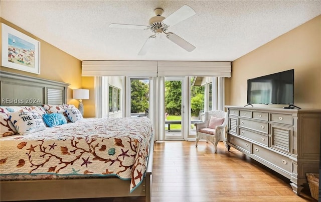 bedroom with ceiling fan, light hardwood / wood-style floors, a textured ceiling, and access to outside