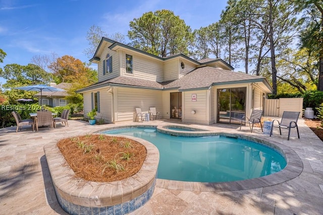 rear view of property featuring a pool with hot tub and a patio area