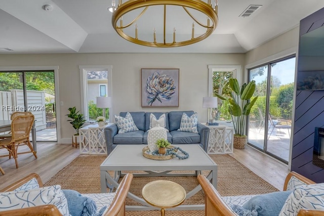 living room featuring lofted ceiling, a tray ceiling, and light hardwood / wood-style flooring