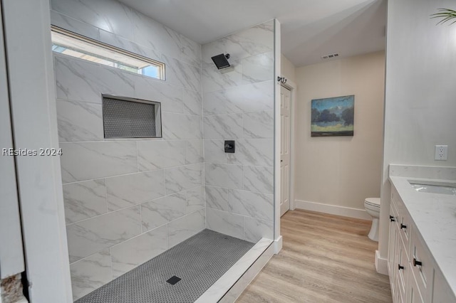 bathroom with tiled shower, vanity, toilet, and hardwood / wood-style floors