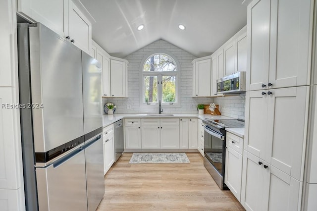 kitchen with white cabinetry, lofted ceiling, stainless steel appliances, and sink