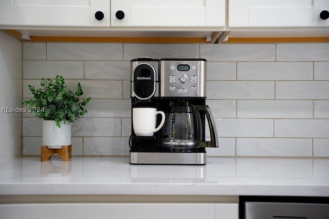 interior details with backsplash, light stone countertops, and white cabinets