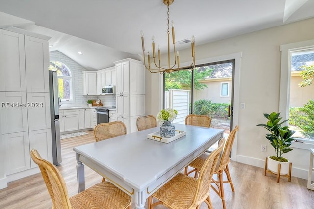 dining space with lofted ceiling, a healthy amount of sunlight, and light hardwood / wood-style floors