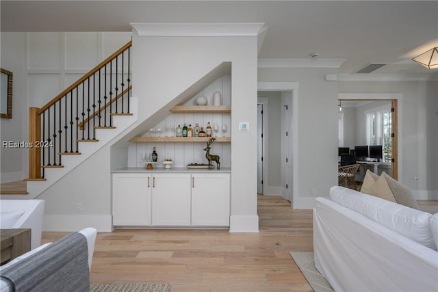 bar with crown molding, white cabinets, and light hardwood / wood-style floors