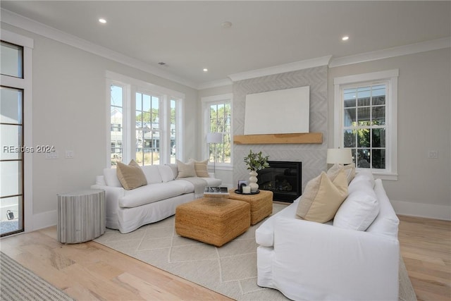 living room featuring a tiled fireplace, light hardwood / wood-style flooring, and ornamental molding