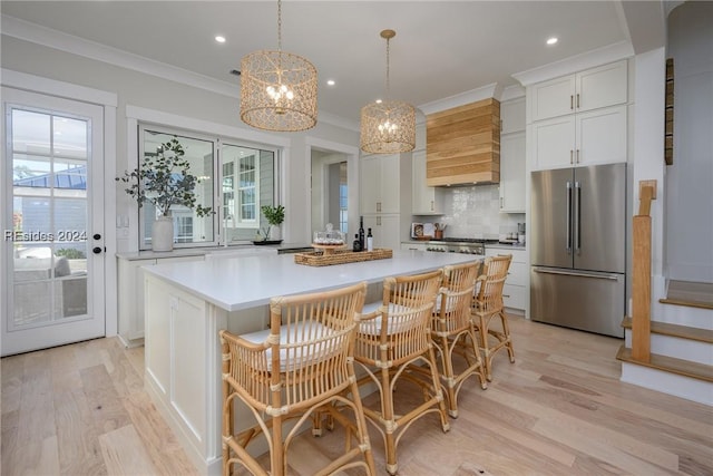 kitchen featuring high end fridge, a center island, tasteful backsplash, white cabinets, and custom exhaust hood