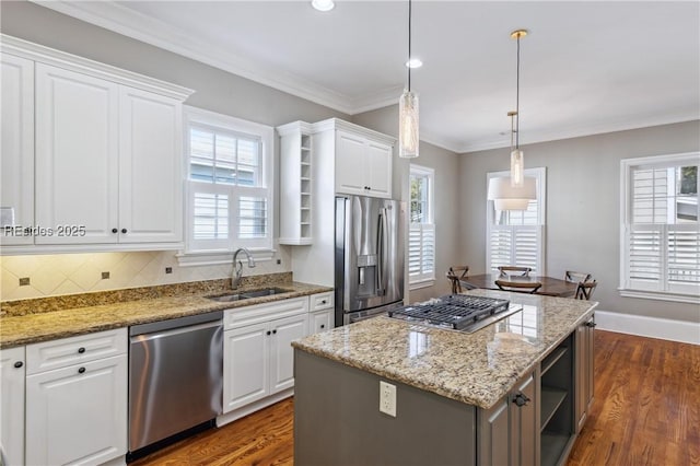 kitchen featuring sink, appliances with stainless steel finishes, a center island, white cabinets, and decorative light fixtures