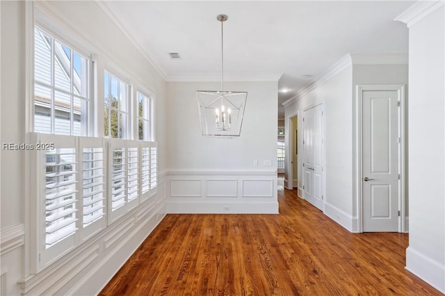 interior space featuring ornamental molding, wood-type flooring, and an inviting chandelier