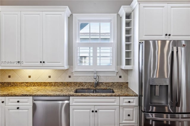 kitchen with sink, tasteful backsplash, dark stone countertops, appliances with stainless steel finishes, and white cabinets