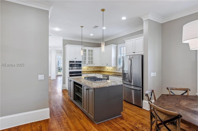 kitchen featuring appliances with stainless steel finishes, a center island, white cabinets, and light stone counters