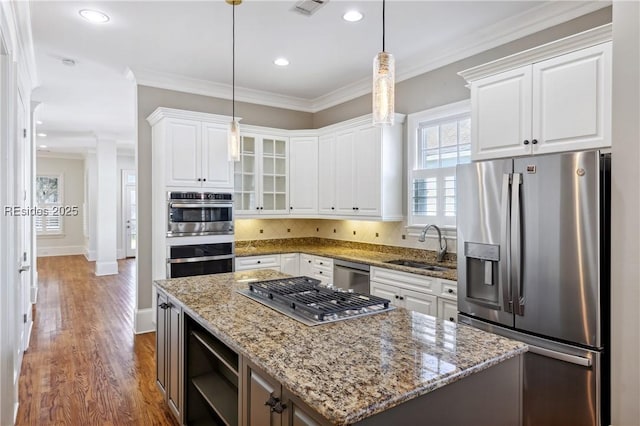 kitchen featuring stainless steel appliances, white cabinetry, a center island, and decorative light fixtures