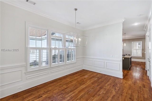 unfurnished dining area featuring an inviting chandelier, ornamental molding, and dark wood-type flooring