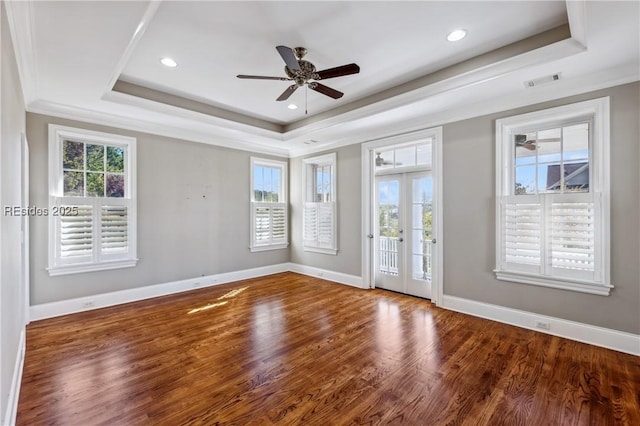 empty room with french doors, a tray ceiling, dark hardwood / wood-style flooring, and crown molding