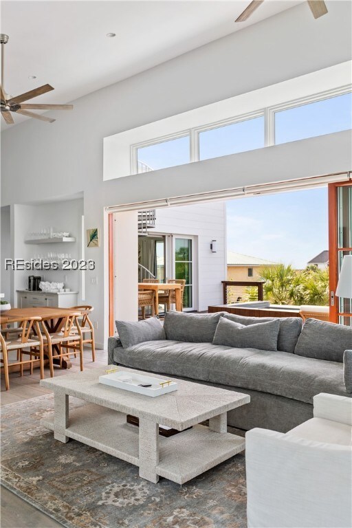 living room with a towering ceiling, a wealth of natural light, and ceiling fan