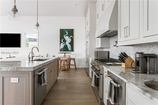 kitchen with sink, high end appliances, light stone counters, hanging light fixtures, and white cabinets