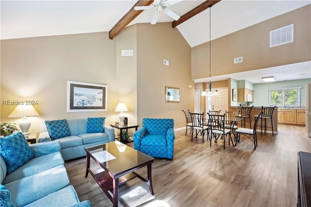 living room with vaulted ceiling with beams, hardwood / wood-style flooring, and ceiling fan with notable chandelier