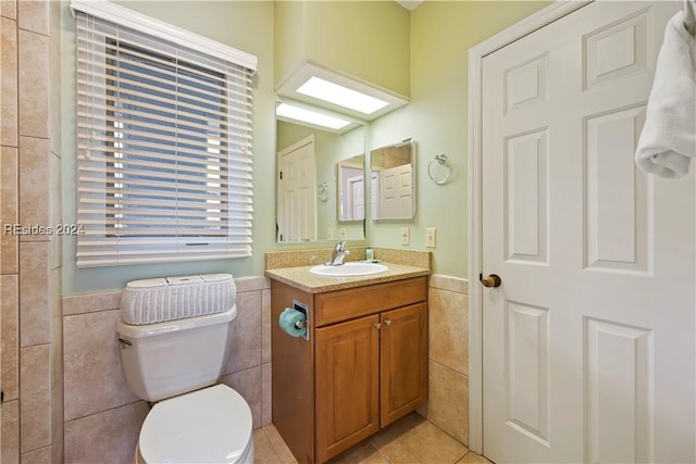 bathroom with vanity, tile walls, tile patterned floors, and toilet