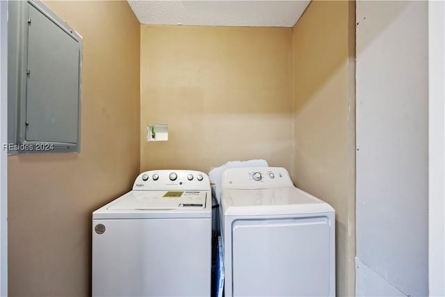 clothes washing area with a textured ceiling, electric panel, and washer and clothes dryer