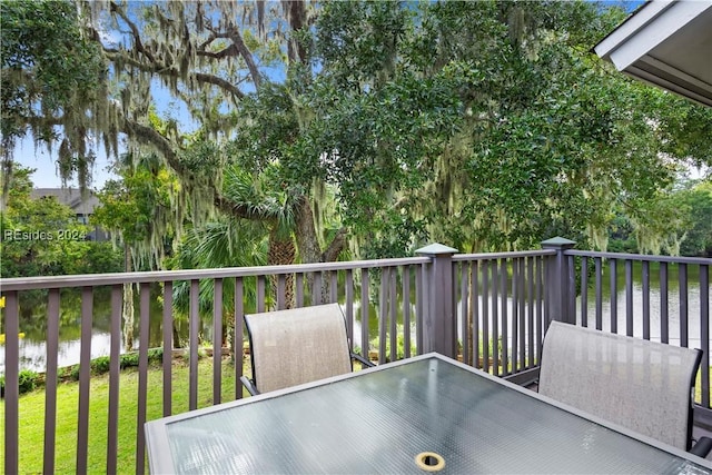 wooden deck with a water view and a lawn