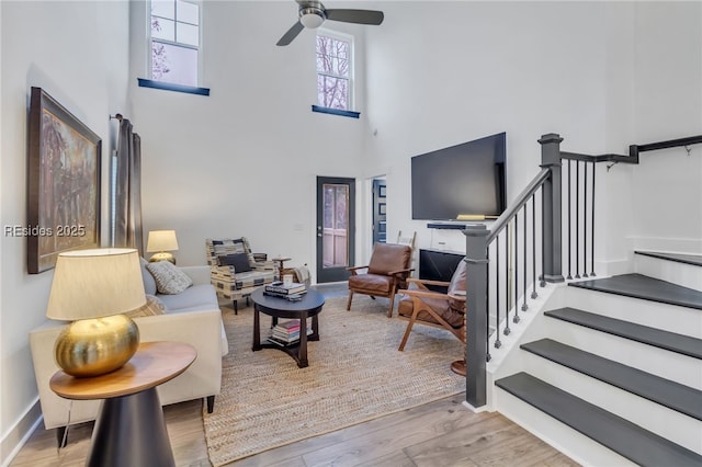 living room featuring a towering ceiling, light hardwood / wood-style flooring, and ceiling fan