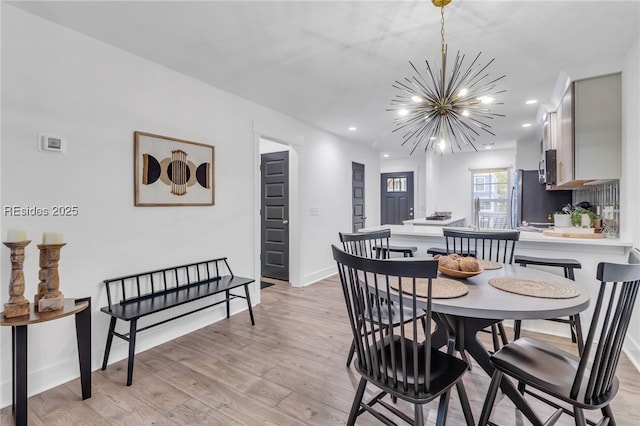 dining area with an inviting chandelier and light hardwood / wood-style flooring