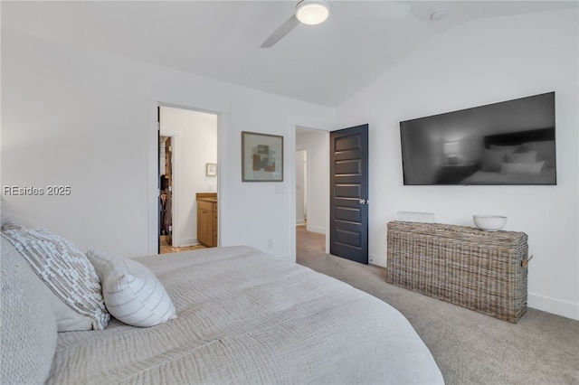 bedroom with ensuite bath, vaulted ceiling, light colored carpet, and ceiling fan