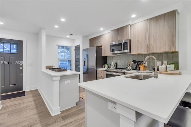 kitchen with stainless steel appliances, kitchen peninsula, sink, and decorative backsplash